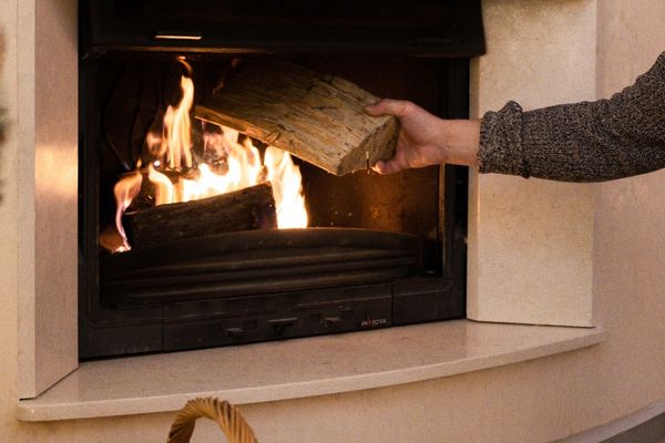 Man putting kiln-dried firewood into a fireplace