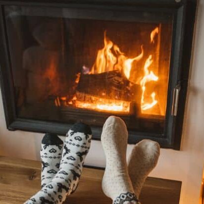 Couple warming their feet by a wood-burning fireplace