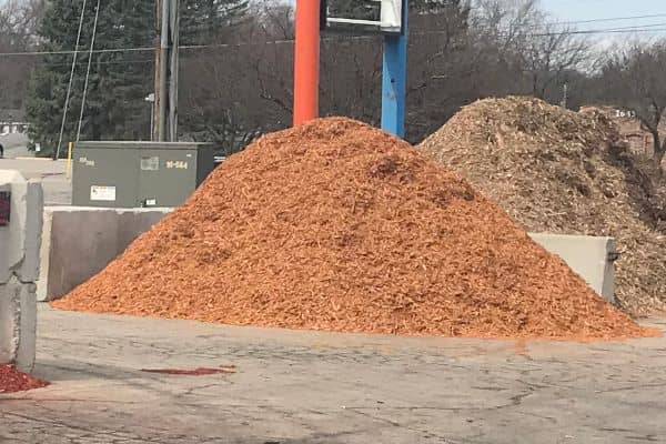 A pile of gold mulch in front of a sign