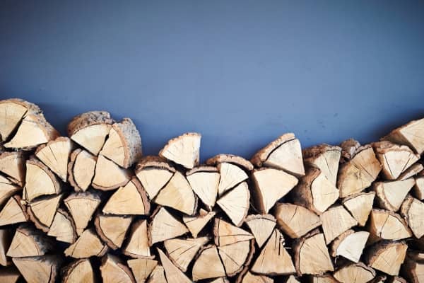 Neatly stacked firewood against blue background