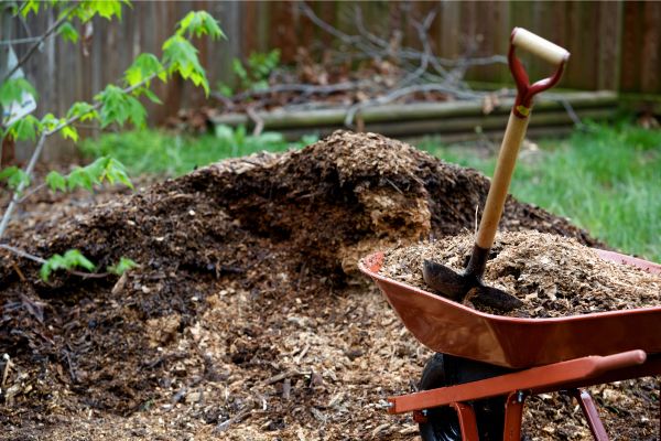 A pile of mulch with a wheelbarrow next to it