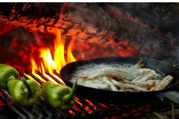 Food is being cooked over a roaring campfire